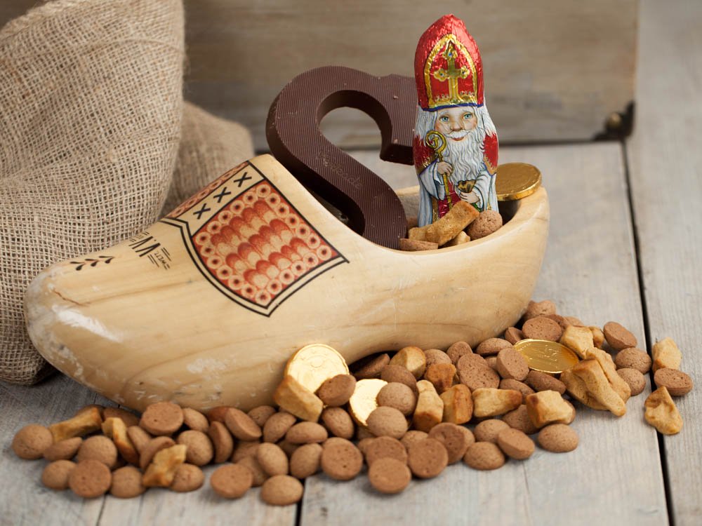 A wooden shoe filled with Saint Nicholas delicacies such as Choclate Letters, Pepernuts, Spicy nuts, and choclate coins.